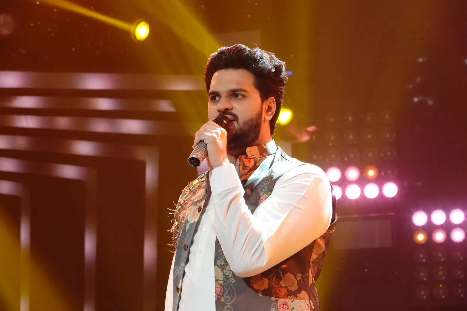 A singer performing under stage lights at a live event